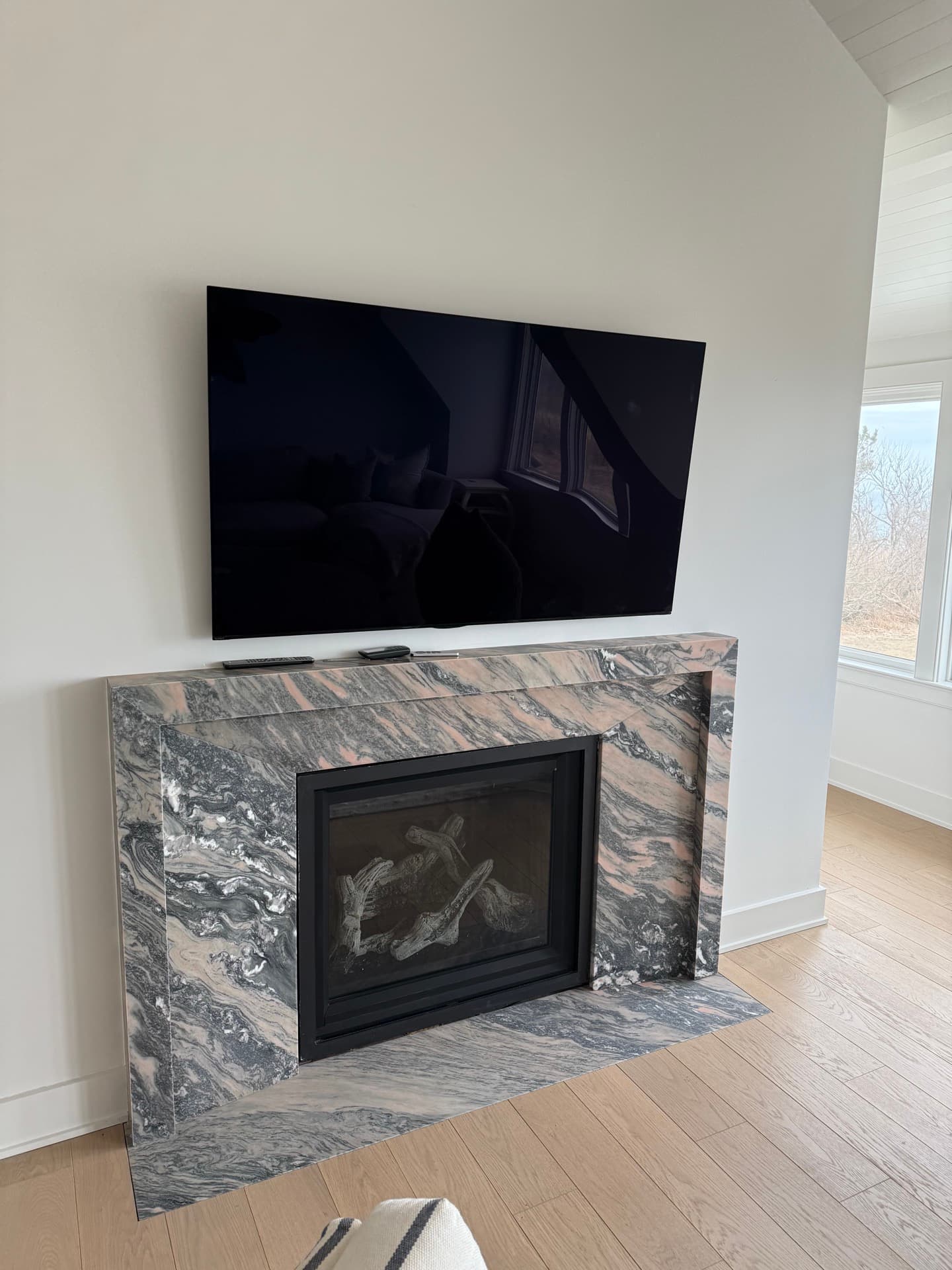 Living room with a wall-mounted television above a marble fireplace
